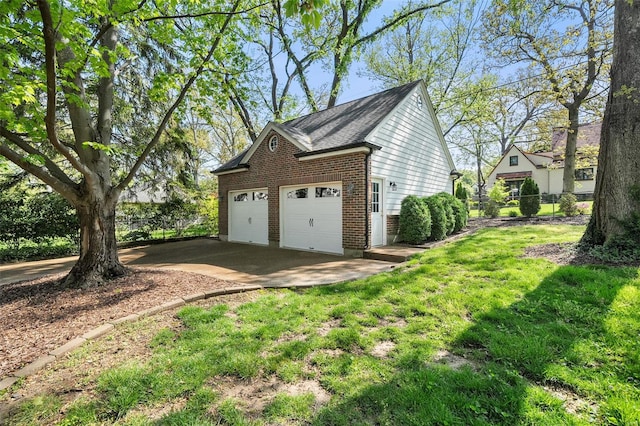 view of side of property with a detached garage, brick siding, fence, and a lawn