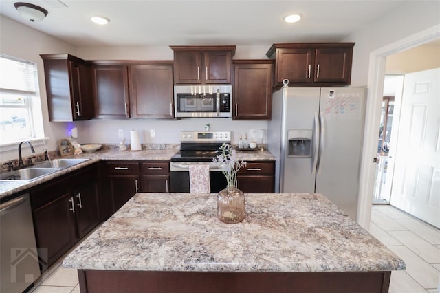 kitchen featuring light tile patterned flooring, dark brown cabinets, stainless steel appliances, and a sink