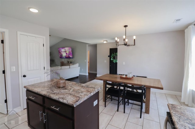 kitchen featuring a center island, baseboards, visible vents, a chandelier, and pendant lighting