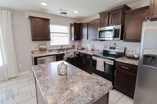 kitchen featuring a center island, a sink, dark brown cabinetry, stainless steel appliances, and visible vents
