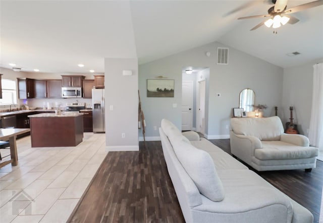 living area with lofted ceiling, a ceiling fan, light wood-style floors, and visible vents