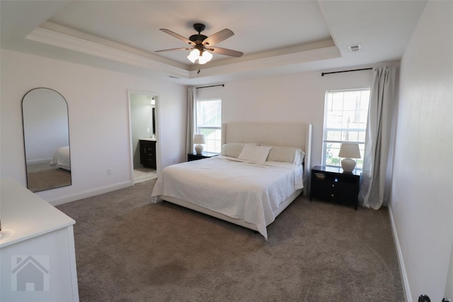 bedroom with carpet, a raised ceiling, visible vents, ensuite bath, and baseboards