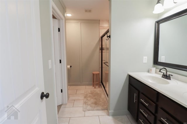full bathroom featuring tile patterned flooring, double vanity, a sink, baseboards, and a stall shower