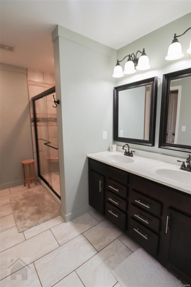 full bath featuring double vanity, a shower stall, tile patterned flooring, and a sink
