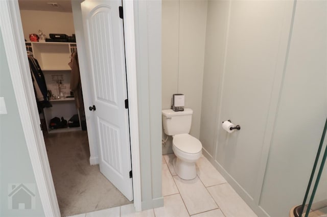 bathroom featuring a spacious closet, toilet, and tile patterned floors