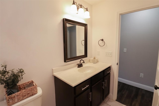 half bath with tile patterned flooring, baseboards, toilet, and vanity