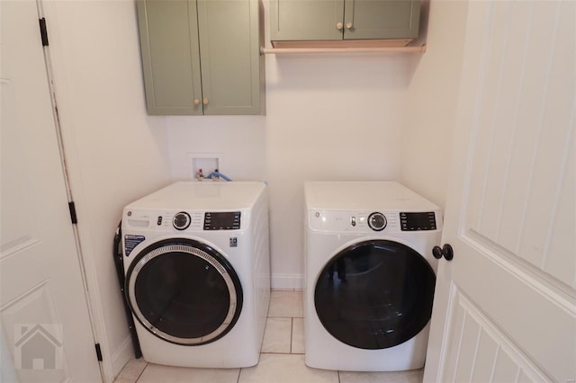 washroom featuring baseboards, washer and dryer, light tile patterned floors, and cabinet space