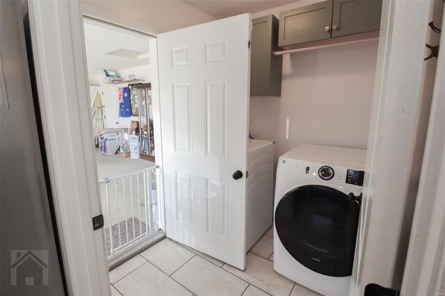 laundry room with cabinet space, washer and clothes dryer, and light tile patterned floors