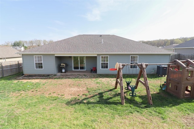 back of house with roof with shingles, central AC, fence, and a lawn