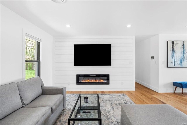 living room featuring recessed lighting, baseboards, wood finished floors, and a fireplace