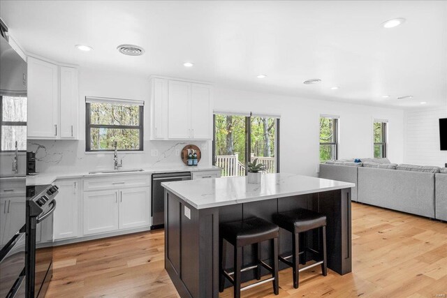 kitchen featuring stainless steel dishwasher, decorative backsplash, black electric range oven, white cabinets, and a sink