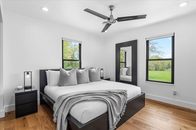 bedroom featuring baseboards, multiple windows, and light wood-type flooring