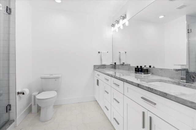 bathroom featuring double vanity, toilet, tiled shower, recessed lighting, and a sink