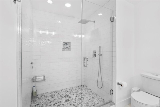 bathroom featuring recessed lighting, toilet, and a shower stall