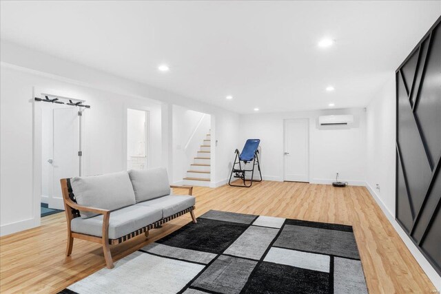 sitting room featuring stairway, a wall mounted AC, recessed lighting, and light wood-style flooring