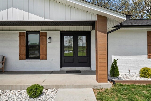entrance to property featuring brick siding, french doors, and a porch