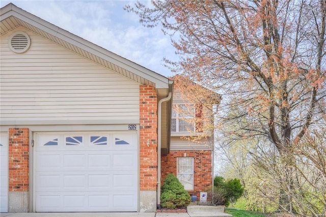 view of side of property featuring brick siding and a garage