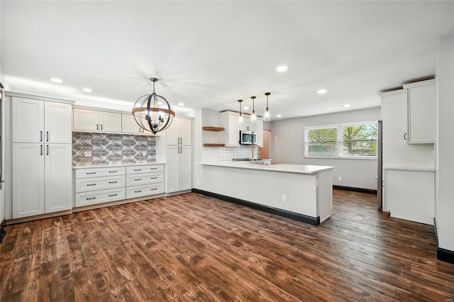 kitchen featuring tasteful backsplash, a peninsula, recessed lighting, stainless steel microwave, and light countertops