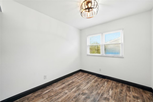 spare room with baseboards and dark wood finished floors