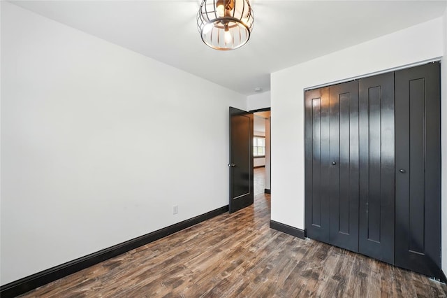unfurnished bedroom with a closet, baseboards, and wood finished floors