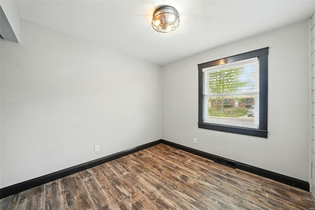 empty room featuring baseboards and dark wood finished floors