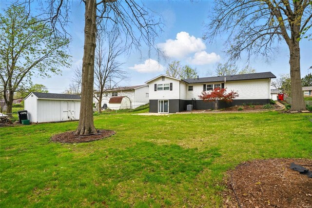 rear view of house featuring fence, an outdoor structure, and a lawn
