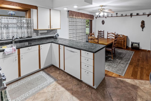 kitchen featuring ceiling fan, backsplash, a sink, a peninsula, and white cabinetry