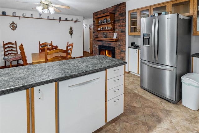 kitchen featuring white cabinets, dark countertops, stainless steel fridge with ice dispenser, a fireplace, and a ceiling fan