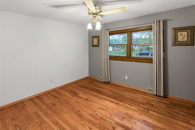 unfurnished room featuring baseboards, wood-type flooring, a ceiling fan, and visible vents