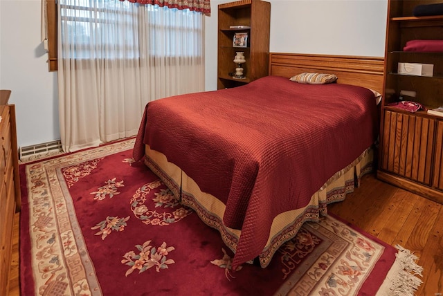 bedroom featuring a baseboard heating unit and wood finished floors