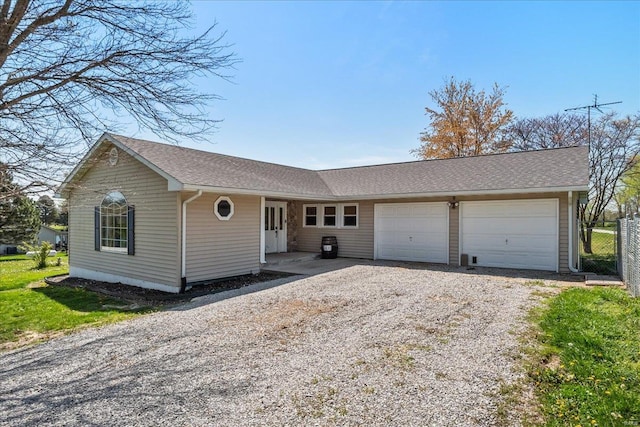 ranch-style home with a garage, driveway, fence, and roof with shingles