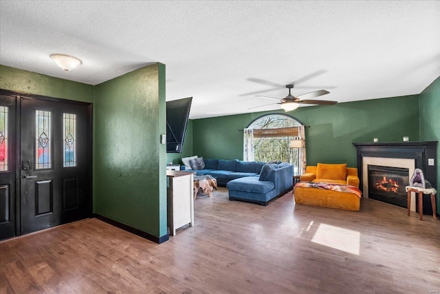 entrance foyer with a glass covered fireplace, a ceiling fan, wood finished floors, and a textured ceiling