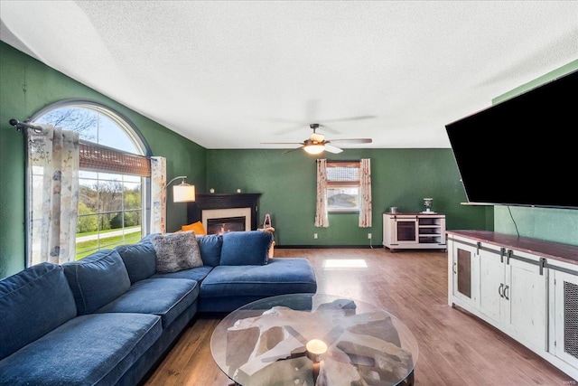 living area with ceiling fan, a healthy amount of sunlight, wood finished floors, and a textured ceiling