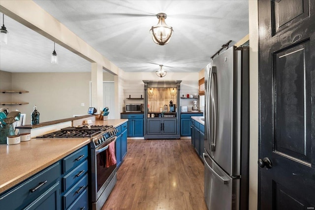 kitchen featuring open shelves, light countertops, blue cabinetry, appliances with stainless steel finishes, and dark wood-type flooring