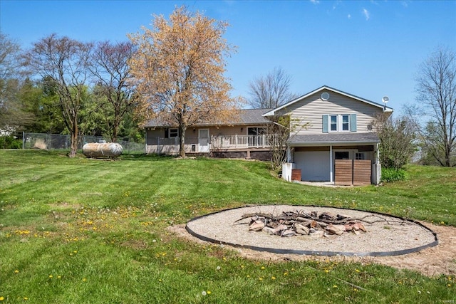 rear view of house with a yard, an outdoor fire pit, and fence