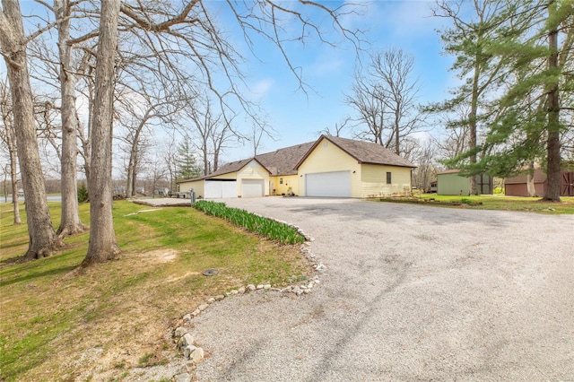 view of front facade featuring a detached garage, a front lawn, and driveway