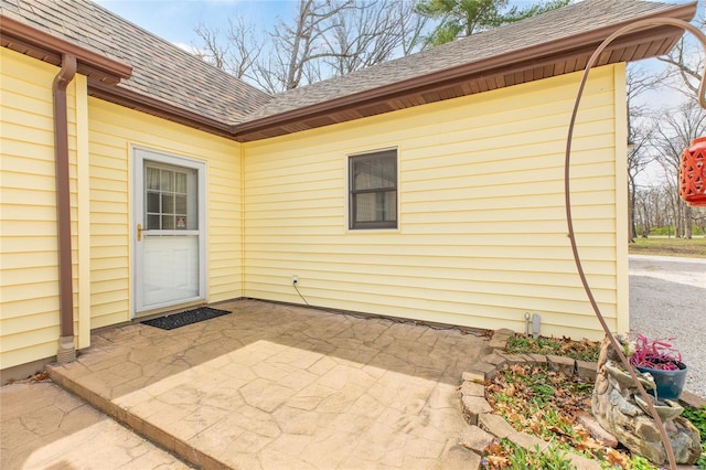 doorway to property with a patio area and a shingled roof