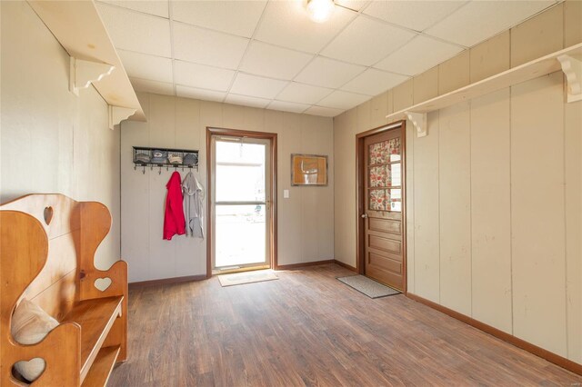interior space with a paneled ceiling, baseboards, and wood finished floors
