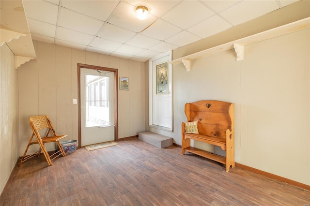 living area featuring a paneled ceiling, wood finished floors, and baseboards