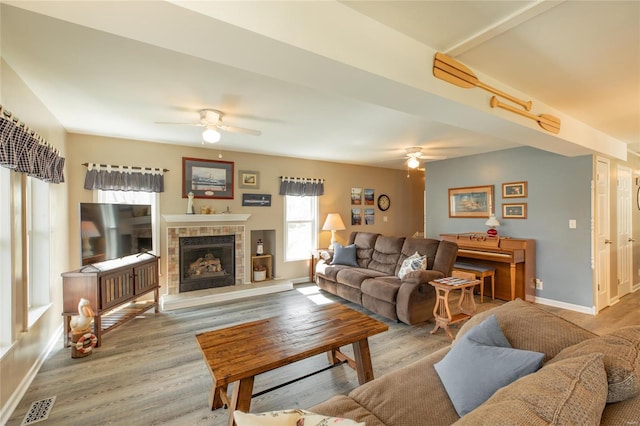 living room featuring visible vents, baseboards, wood finished floors, and ceiling fan