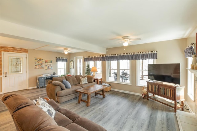 living area with baseboards, a ceiling fan, and wood finished floors
