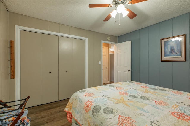 bedroom with a textured ceiling, wood finished floors, a closet, and a decorative wall