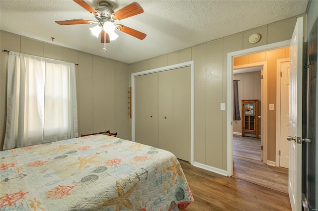 bedroom with a closet, a textured ceiling, a ceiling fan, and wood finished floors