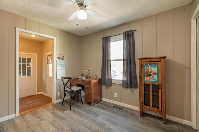 home office featuring a textured ceiling, wood finished floors, ceiling fan, and visible vents