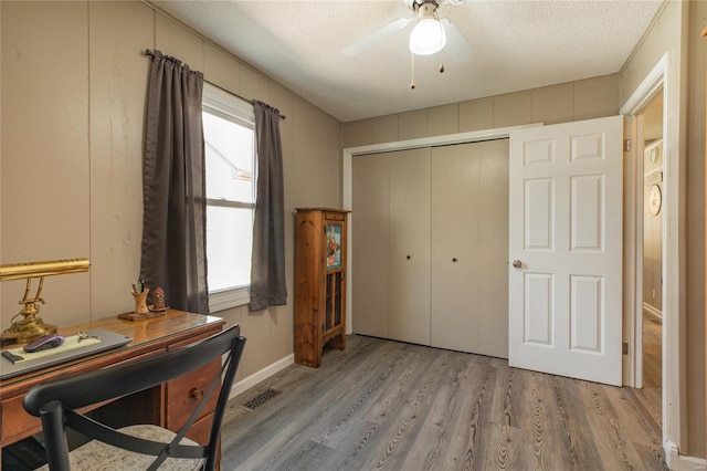 interior space with visible vents, a ceiling fan, wood finished floors, and a textured ceiling