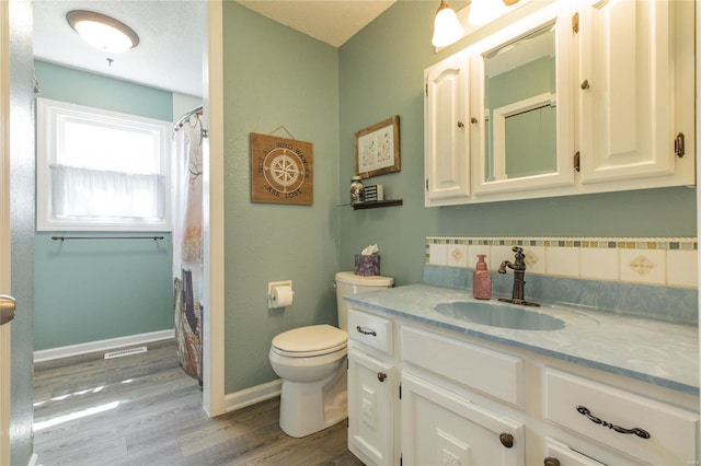 full bath with visible vents, baseboards, toilet, vanity, and wood finished floors