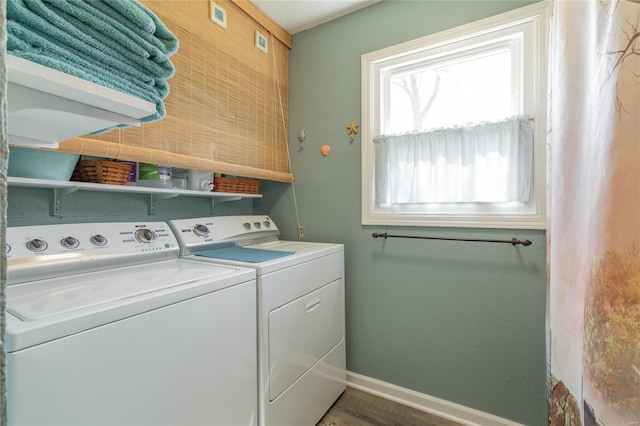 clothes washing area with washing machine and dryer, laundry area, baseboards, and wood finished floors
