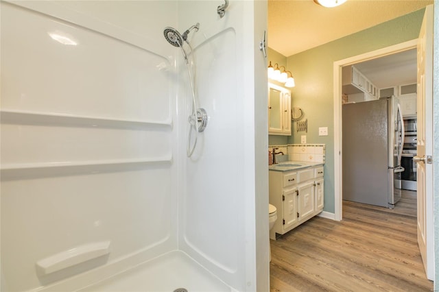 full bathroom featuring toilet, a shower, vanity, and wood finished floors