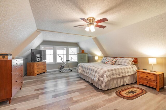 bedroom with a textured ceiling, lofted ceiling, and light wood-type flooring