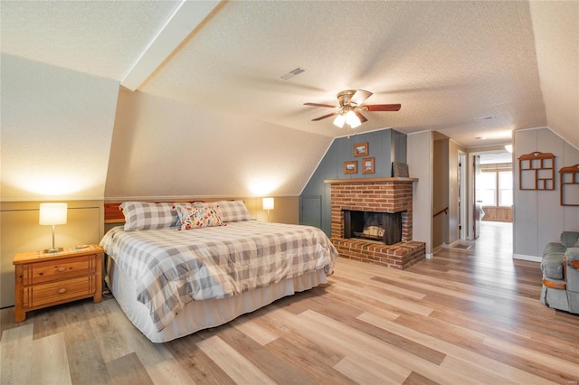 bedroom featuring a textured ceiling, light wood finished floors, lofted ceiling, and visible vents